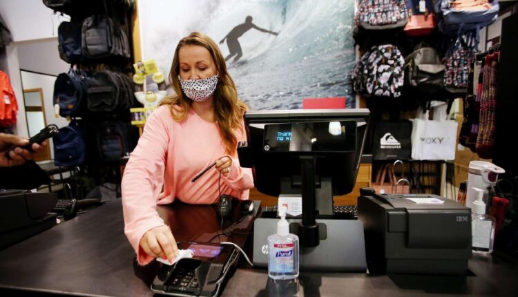 Liz Atkinson, manager of the Quicksilver store at the Outlets at Traverse Mountain in Lehi, cleans a terminal after a transaction on May 1, 2020. Many businesses began encouraging transactions with plastic debit and credit cards as a safety measure to fight the spread of COVID-19. Now, a study from BYU says that plastic payment cards are actually worse for carrying the coronavirus than cash and coins.  