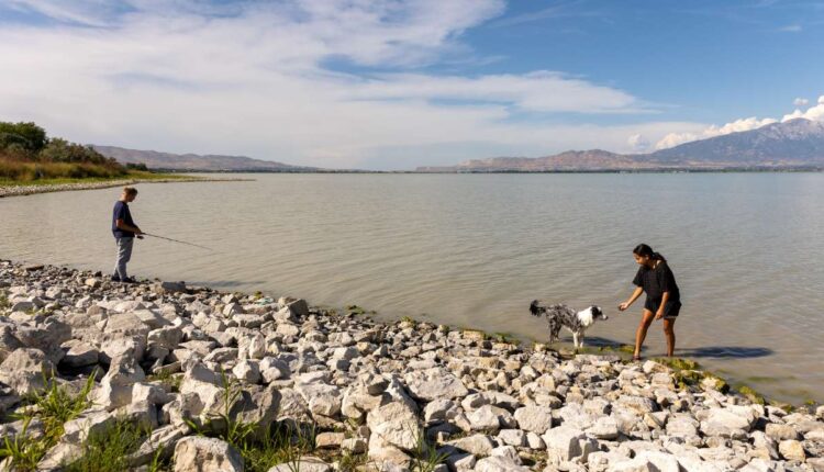 Joshua Larson fishes at Utah Lake while his girlfriend, Katelyn Molen, plays with their dog, Theo, in Saratoga Springs on Monday. A panel of scientific experts from across Utah met Tuesday to discuss what's wrong with the lake and how those issues can be addressed.