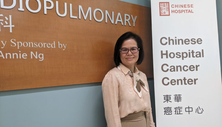 Jian Zhang stands beside a large, vertical sign that says, "Chinese Hospital Cancer Center"